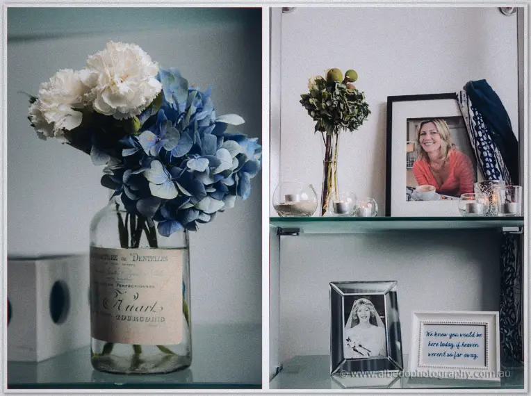 Blue hydrangeas in a vintage labelled bottle flank a shelf of framed family photos and candlelight