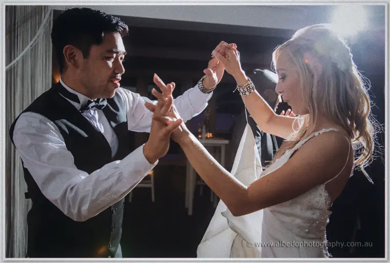 Chris twirls a delighted guest in coral under flare from the dance floor lights behind them