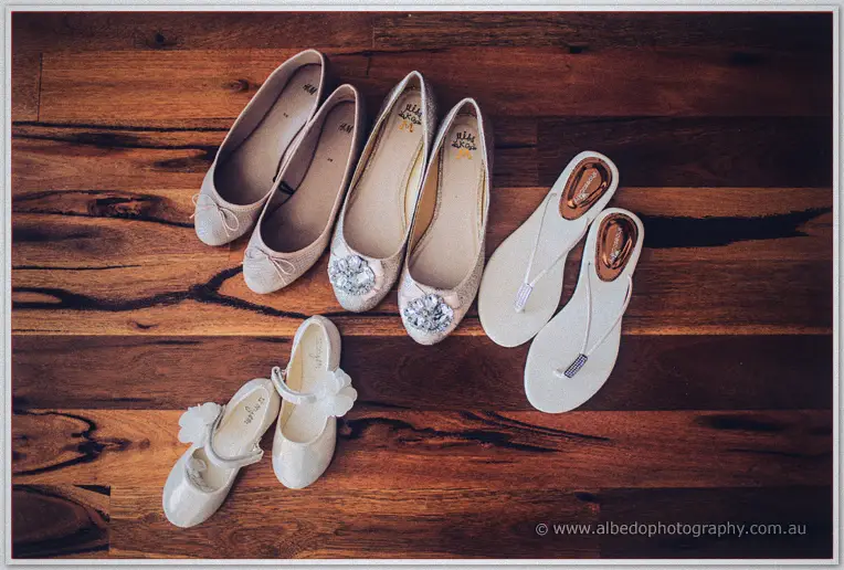 Bridesmaid flats, beaded heels and tiny flower-girl shoes laid out across rich jarrah floorboards