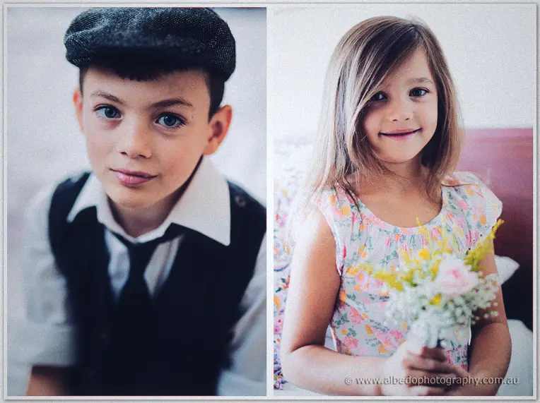 A page boy in a flat cap and a flower girl clutching a small posy beam during wedding preparations