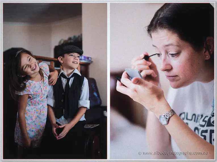 Flower girl and page boy share a laugh while a bridesmaid applies mascara using a hand mirror