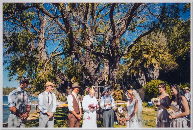 Tansy and Ciaran exchange vows beneath a vast peppermint tree with the celebrant between them