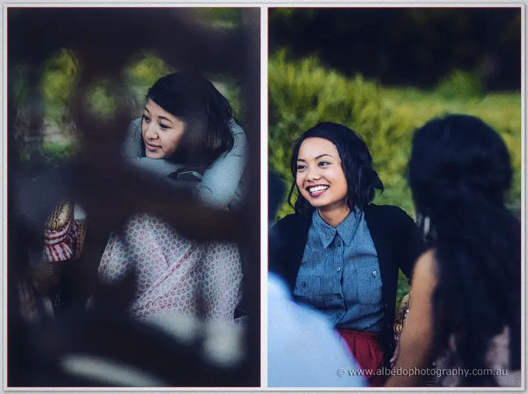 A guest in a denim shirt laughs with friends on the picnic rugs in soft bush light