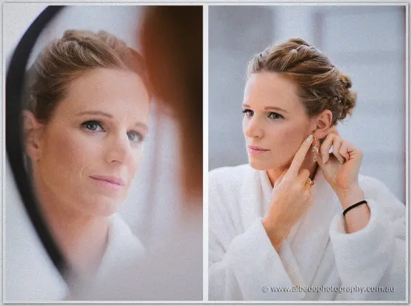 Bride reflected in a round mirror fastening earrings, hair swept into a soft braided updo.