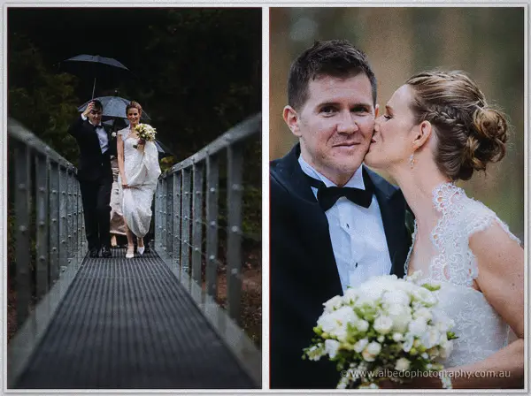 Couple crosses a steel footbridge under umbrellas, then the bride kisses her groom's cheek close up.