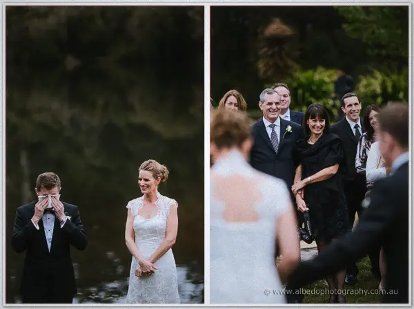 Groom wipes away tears as his bride laughs, guests smiling behind them at the ceremony.