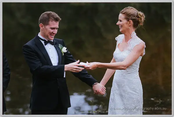 Laughing bride hands her groom a tissue as they hold hands during the ceremony.