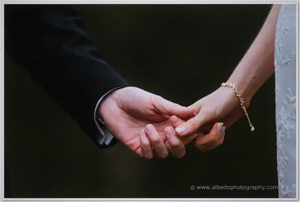 Bride and groom clasping hands in close-up, her gold bracelet catching soft light at Silkwood Winery.