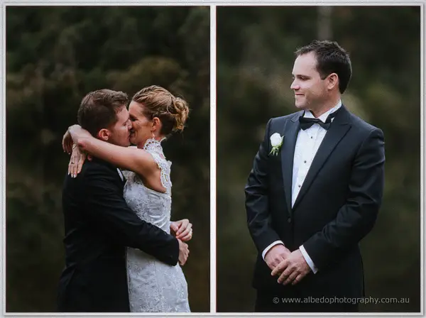 Newlyweds embrace by the dark lake while a smiling groomsman looks on from the trees.