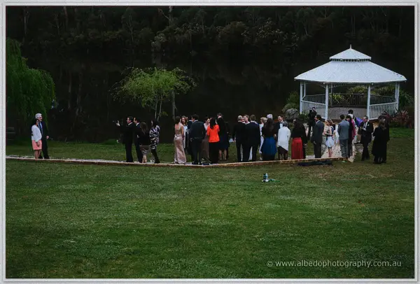 Guests strolling a lakeside lawn toward the white gazebo in the soft dusk light at Silkwood Winery.