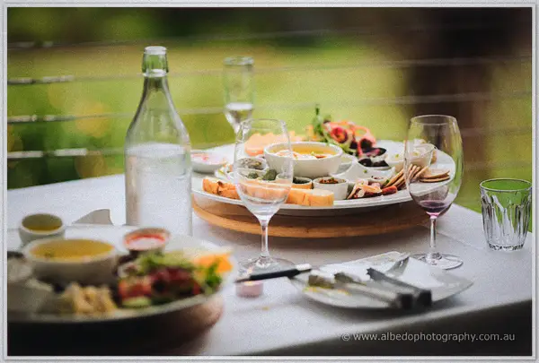 Grazing table of dips, breads and wine glasses arranged on the veranda in soft daylight.
