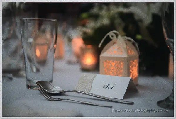 Reception place setting with a monogrammed card, cutlery and a glowing paper lantern.