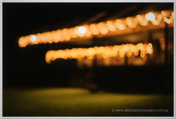 Strings of festoon lights blurring softly along the veranda roofline after dark.