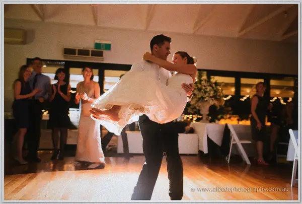 Groom swinging his laughing bride into his arms on the polished dance floor.