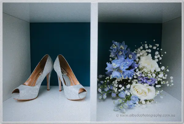 Lace peep-toe heels and a posy of blue delphinium, hydrangea and white roses styled in a white cubby