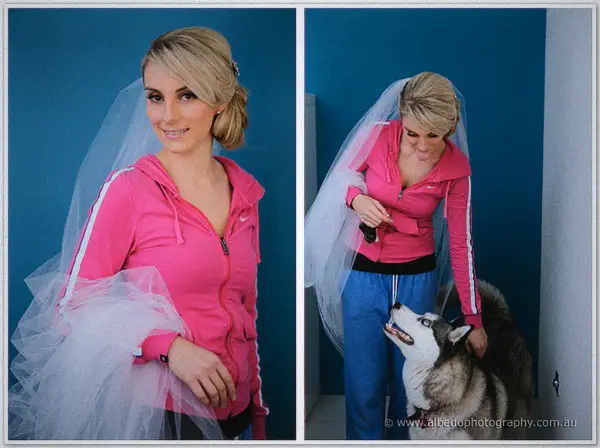 Veiled Sarah in a pink hoodie poses by a blue wall, then giggles as a husky looks up at her
