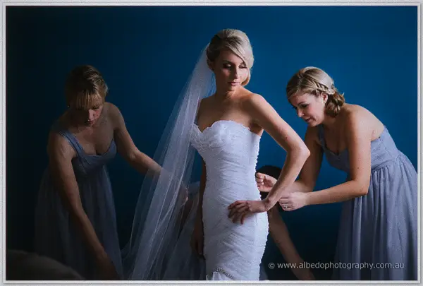 Two bridesmaids in grey chiffon smooth Sarah's ruched gown and veil as she checks her bracelet