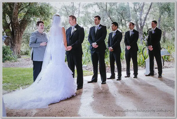 Sarah's cathedral train pools on the stone as the celebrant addresses the couple and groomsmen