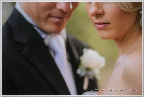 An intimate close-up of the newlyweds, Nathan's white rose boutonniere sharp against Sarah's profile