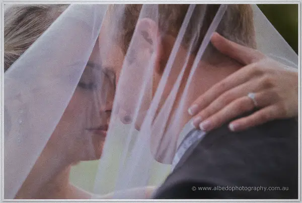 Under a billowing veil, Sarah rests her ringed hand on Nathan's shoulder as the newlyweds lean close