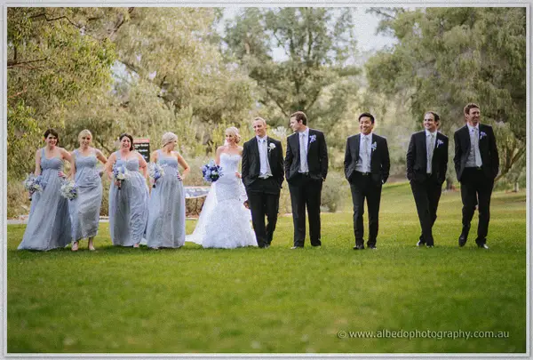The bridal party strolls across a Kings Park lawn with Sarah and Nathan laughing at the centre
