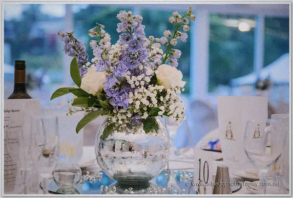 Purple delphiniums, roses and baby's breath in a mirrored silver vase on table ten at Joondalup