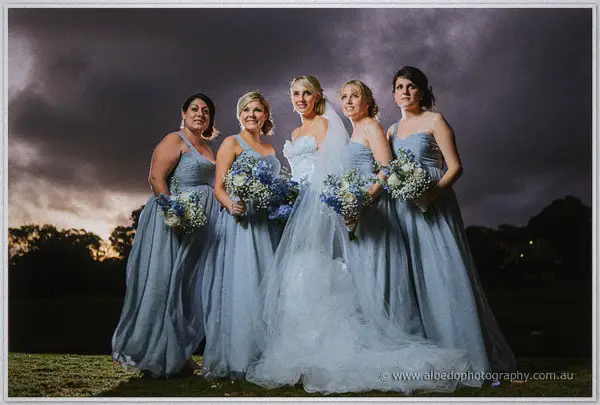 Sarah stands with her four bridesmaids in dove-grey gowns under a heavy dusk sky, bouquets in hand