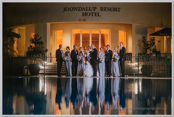 The full bridal party lined up beside the glowing pool at Joondalup Resort Hotel after dark