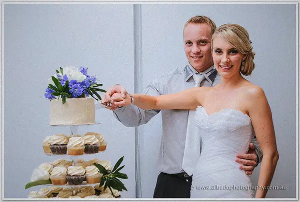 Sarah and Nathan cut their single-tier cake together, cupcake tiers stacked beneath it