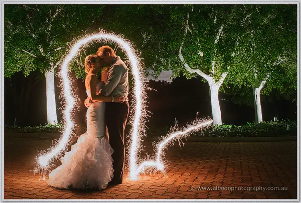 Sarah and Nathan kiss inside a giant sparkler light-painting in the floodlit night gardens of Joondalup Resort