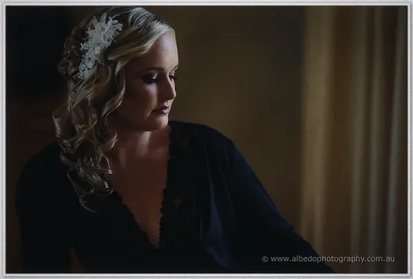A quiet profile of Ashley in black lace, her white floral clip glowing in dim window light