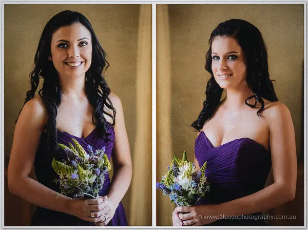Two smiling bridesmaids in strapless plum dresses hold small bouquets of lavender and cream blooms