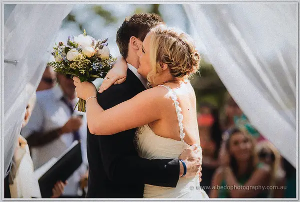 Ashley and Payden kissing under white drapery at their outdoor ceremony
