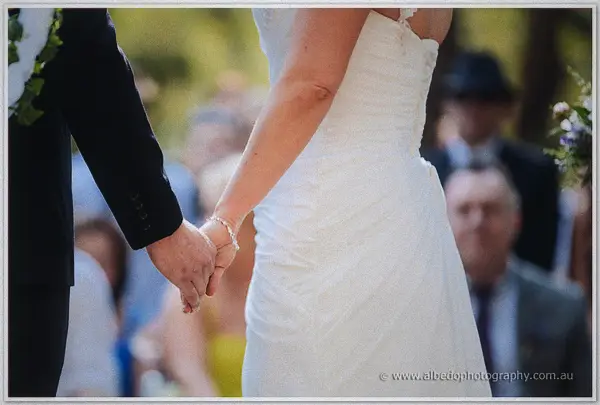 Bride and groom clasping hands before guests at their outdoor ceremony