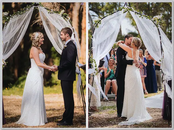 Draped wedding arch framing the couple as they exchange vows and kiss
