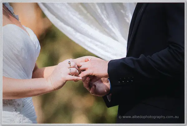Bride carefully sliding the wedding ring onto Payden's finger at the garden ceremony