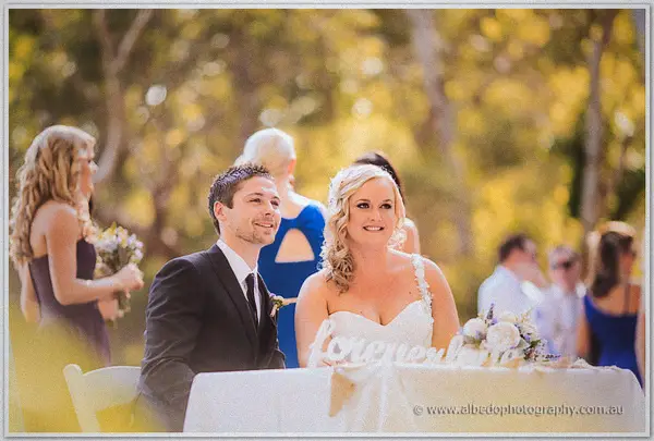 Newlyweds smiling at their sweetheart table during outdoor receptions