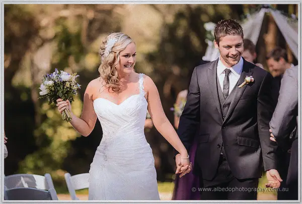 Ashley and Payden laughing as they walk back down the aisle as newlyweds