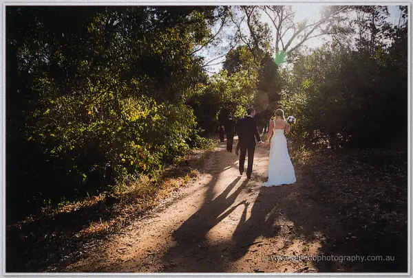 Long shadows trailing the newlyweds along a bush track at sunset