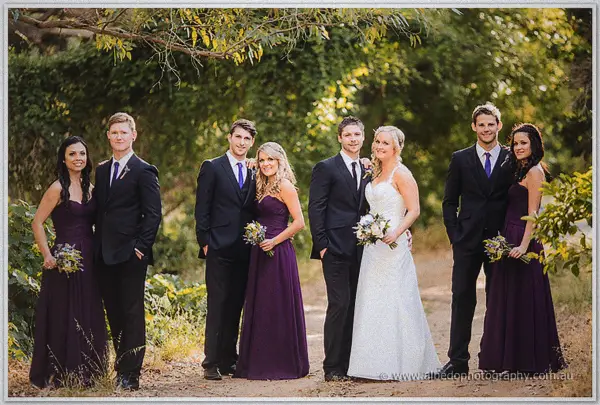 Full bridal party posing in pairs on a gravel drive at Carilley Estate