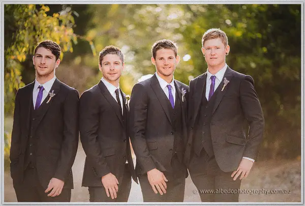 Four groomsmen in charcoal suits standing shoulder to shoulder