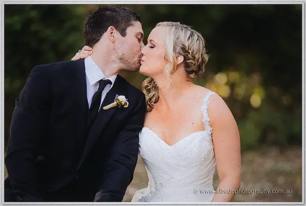 Payden leaning in to kiss Ashley amid soft greenery after their garden ceremony