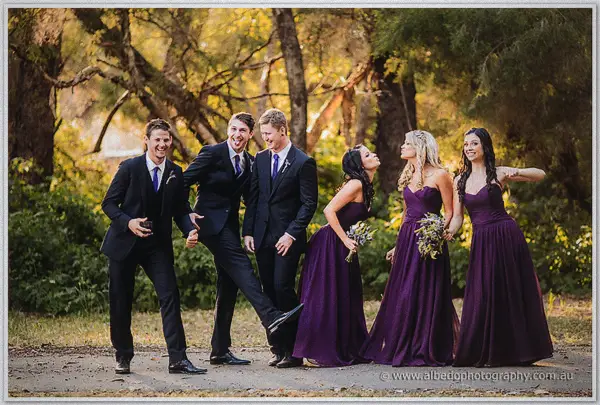 Ashley and Payden's wedding party laughs through a playful group kick on a golden bushland track