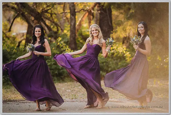 Bridesmaids twirl their flowing plum gowns in the golden light with native bouquets in hand