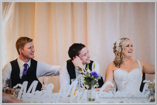 Groomsmen and Ashley burst out laughing at the head table during the wedding speeches