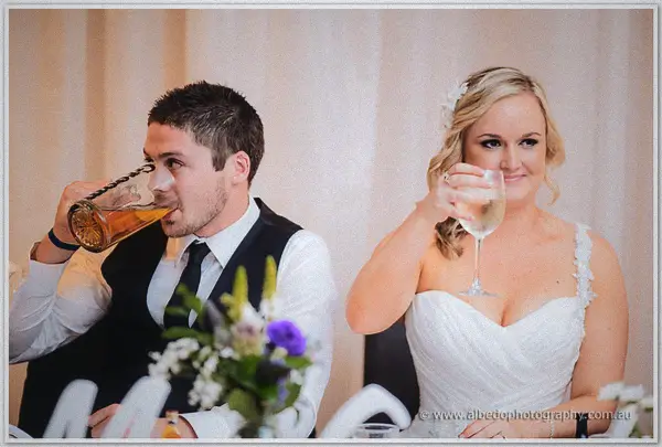 Payden drains a stein of beer while Ashley sips wine together at the head table