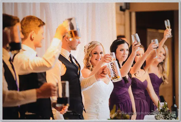 Bridal party raises beer steins and champagne flutes in a toast beside the laughing bride