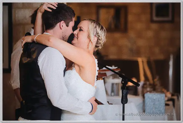 Ashley wraps her arms around Payden's neck during their first dance in the stone-walled barn