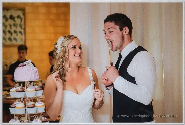 Payden licks frosting from a serving spoon as Ashley grins beside their pink cupcake tower