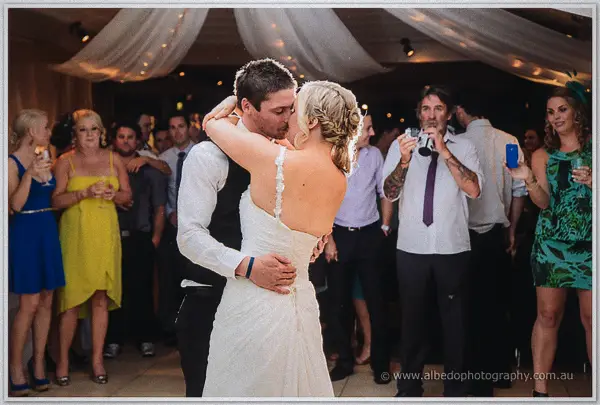 Ashley and Payden kiss mid-dance surrounded by cheering guests beneath draped fairy lights